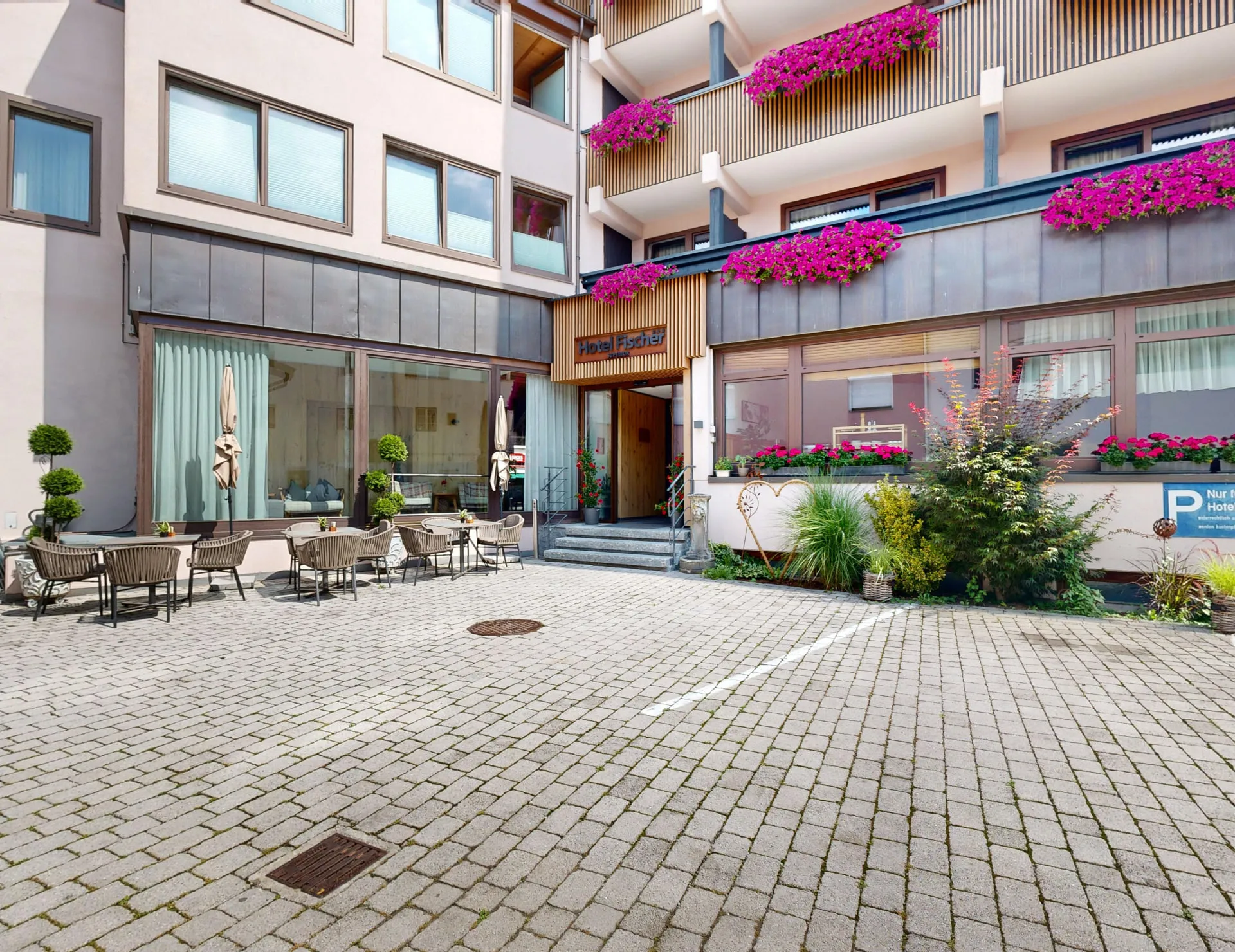 Eingangsbereich des Hotel Fischer mit Terrasse und Blumenbalkonen