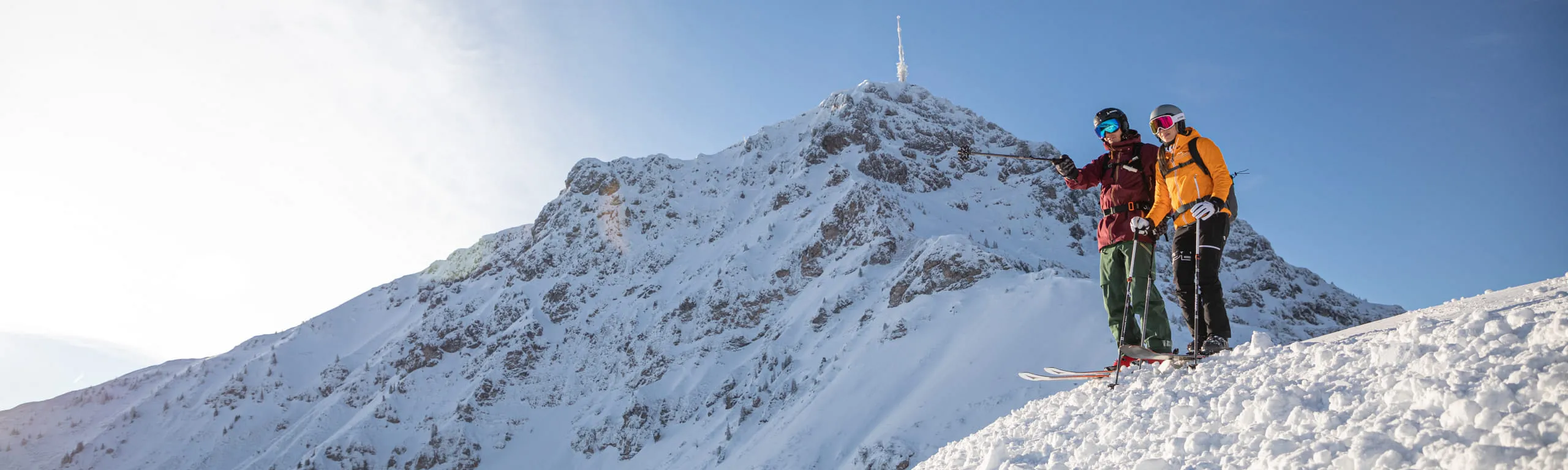 Zwei Skifahrer am verschneiten Harschbichl in St. Johann in Tirol bei Sonnenschein