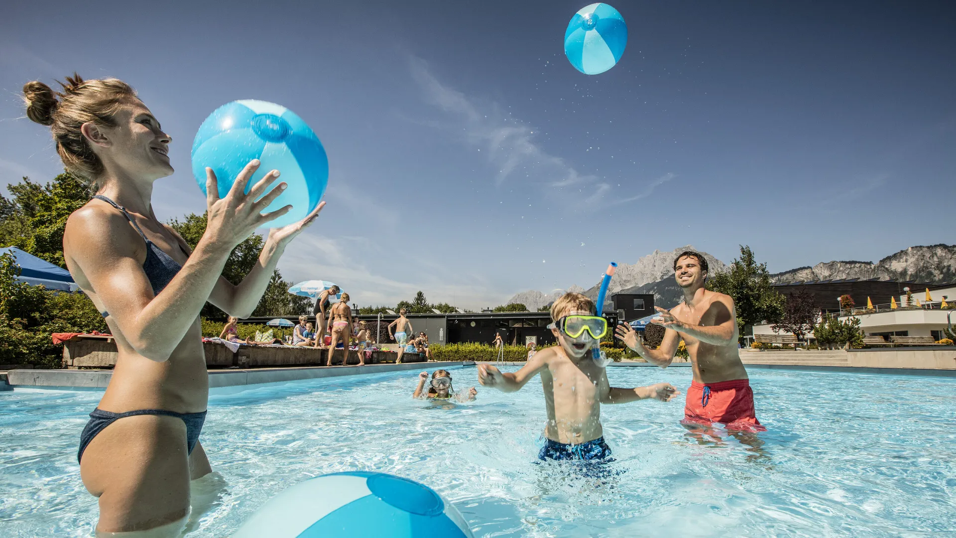 Familie spielt mit Wasserbällen im Freibecken der Panorama Badewelt in St. Johann in Tirol