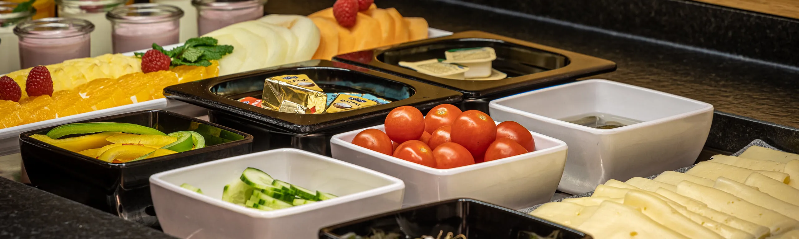 Frühstücksbuffet im Hotel Fischer mit Joghurt, frischem Obst, Gemüse, Käse und Würstchen